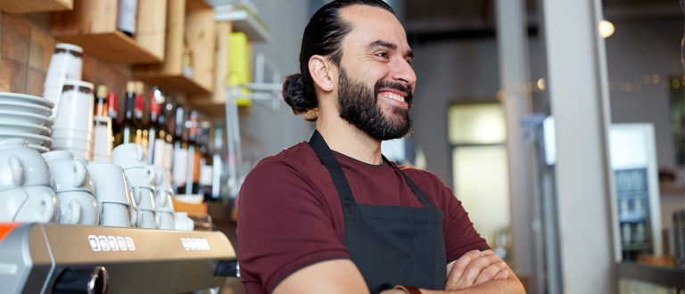 En smilende mann som jobber på kafé